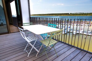 A balcony with a table and chairs, overlooking a marina with boats. - The Generous (03) - Z1-THE HOUSE (Zwenkau)