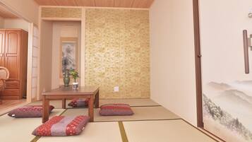 A traditional Japanese room with tatami flooring, a low table with cushions, and a sliding door.