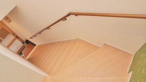 Una escalera de madera con barandilla que conduce a un rellano con piso de madera.