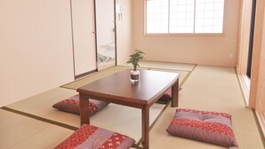 Una habitación japonesa tradicional con suelo de tatami, una mesa de madera baja y cojines.