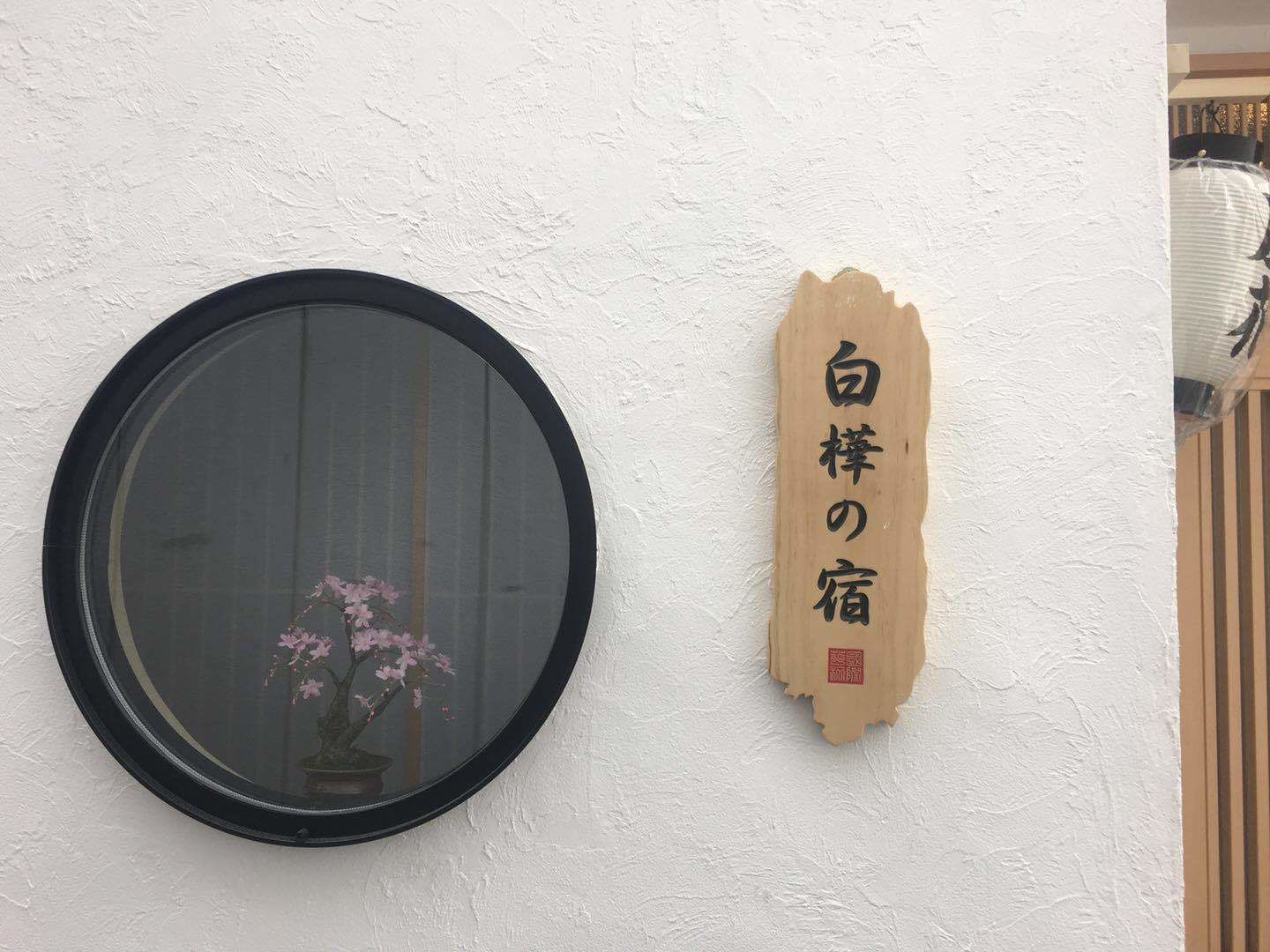 A round mirror with a black frame and a wooden plaque with Japanese characters.