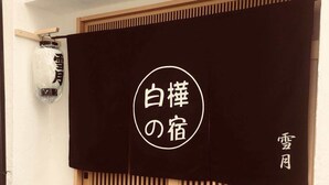 Una entrada tradicional japonesa con un puertas correderas y un farol colgante.