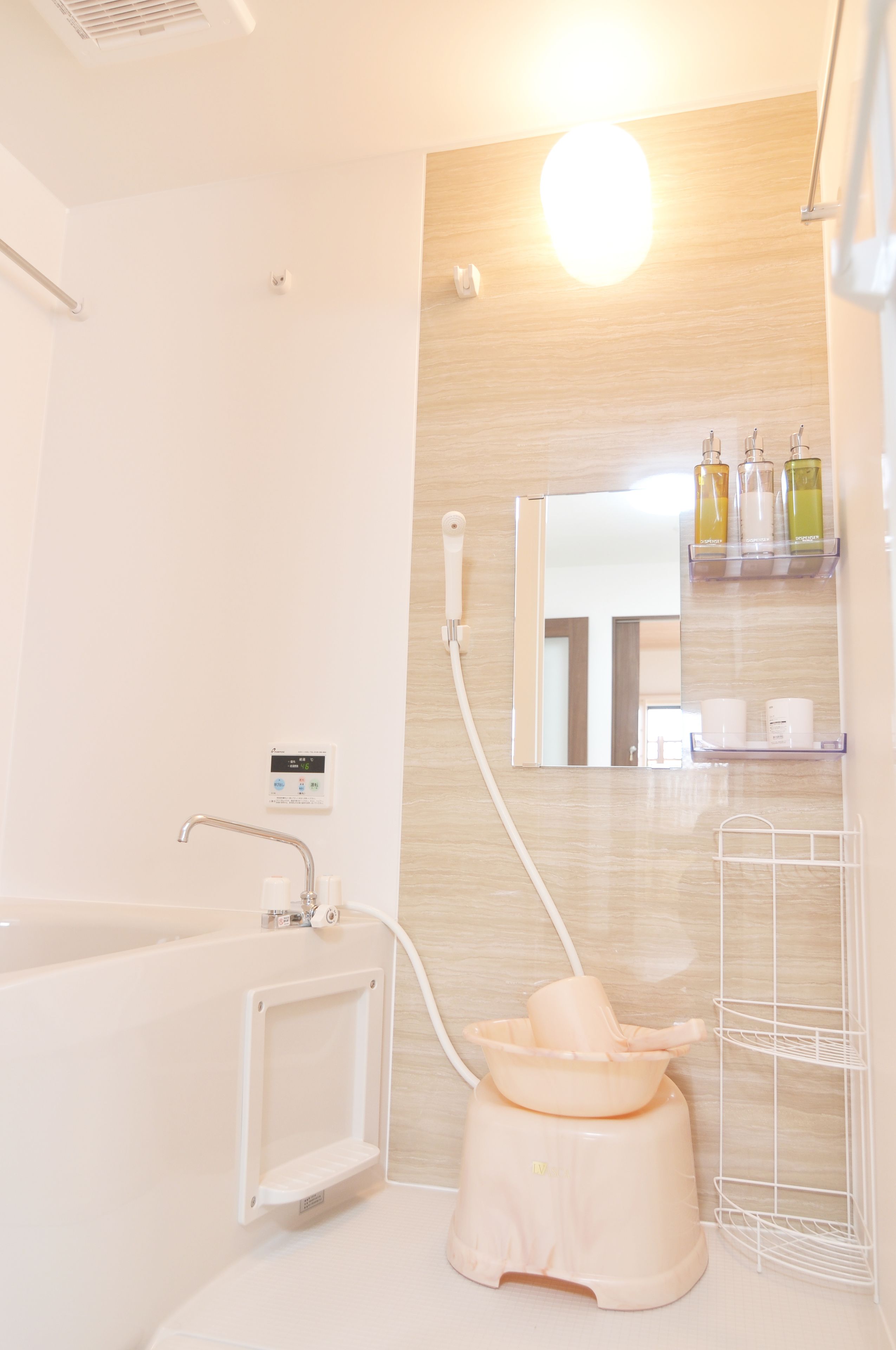 A modern bathroom with a bathtub, a handheld showerhead, a wall-mounted mirror, and a shelf with toiletries.