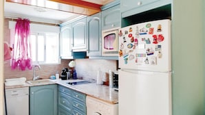 Una cocina compacta con lavadora, lavaplatos y refrigerador decorado con imanes.