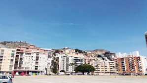 Zona residencial costera con edificios de varios pisos, cielo despejado y un estacionamiento.