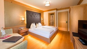 A hotel room with a bed, bedside tables, a desk, a chair, a television, and a wardrobe. - Rauriser Goldzimmer Classic - Hotel Alpina **** (Rauris)