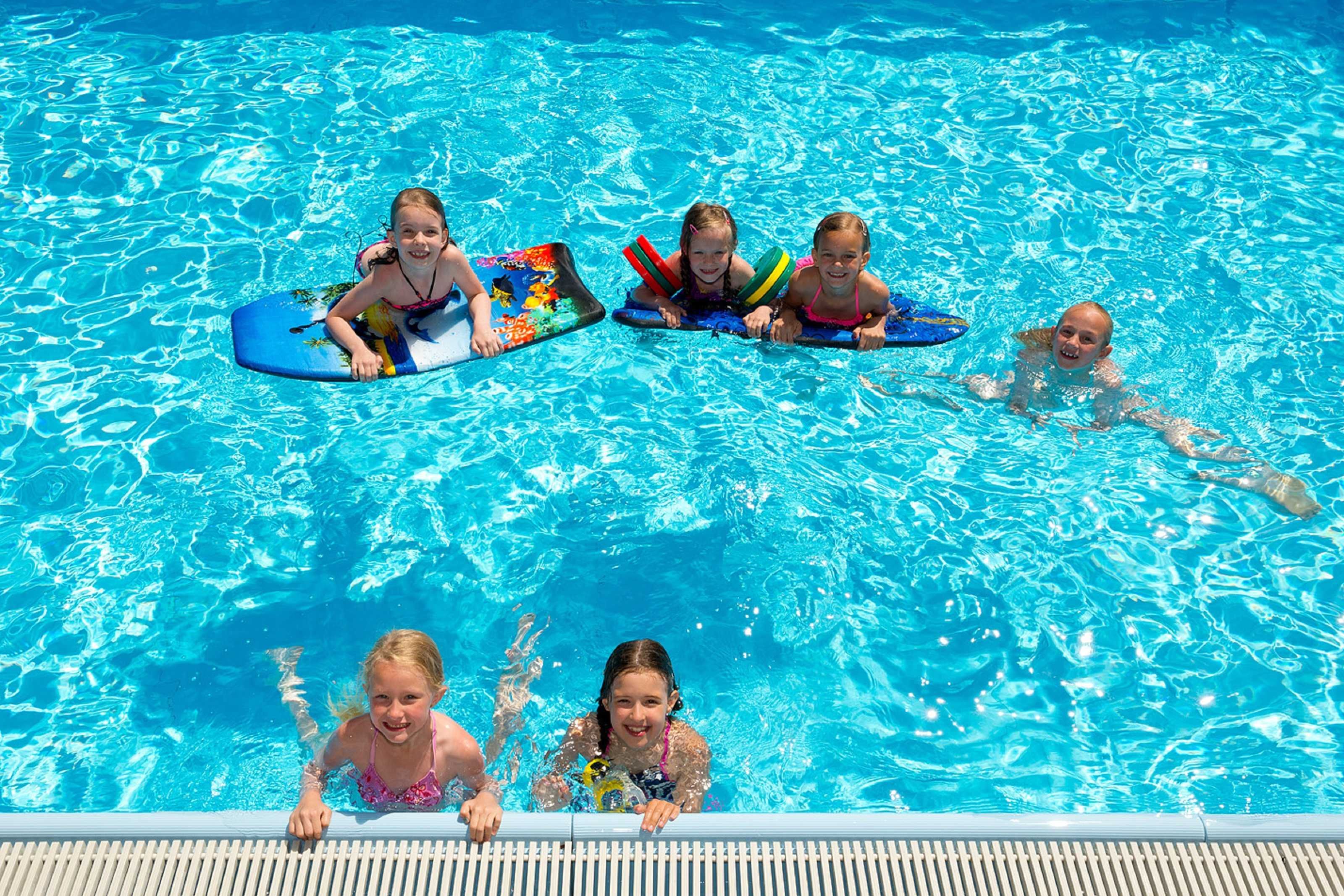 A swimming pool with clear blue water and a wooden deck.