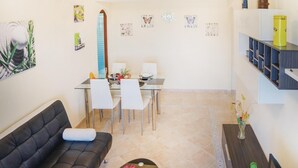 Ein modernes Wohnzimmer mit Sofa, Esstisch, Stühlen und Bildern an den Wänden.
