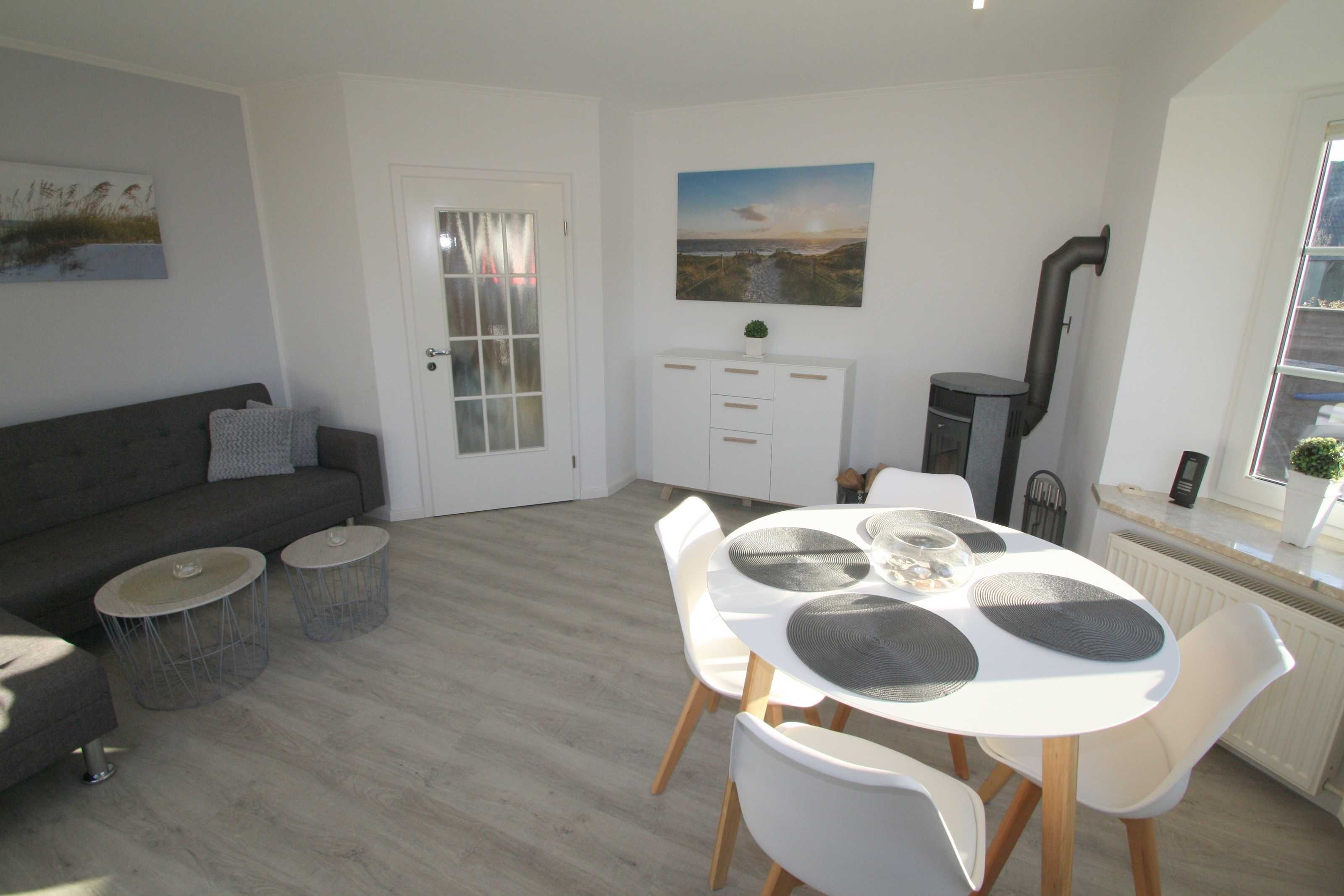 En moderne stue med en grå sofa, et spisebord med hvide stole og et hvidt skab.
