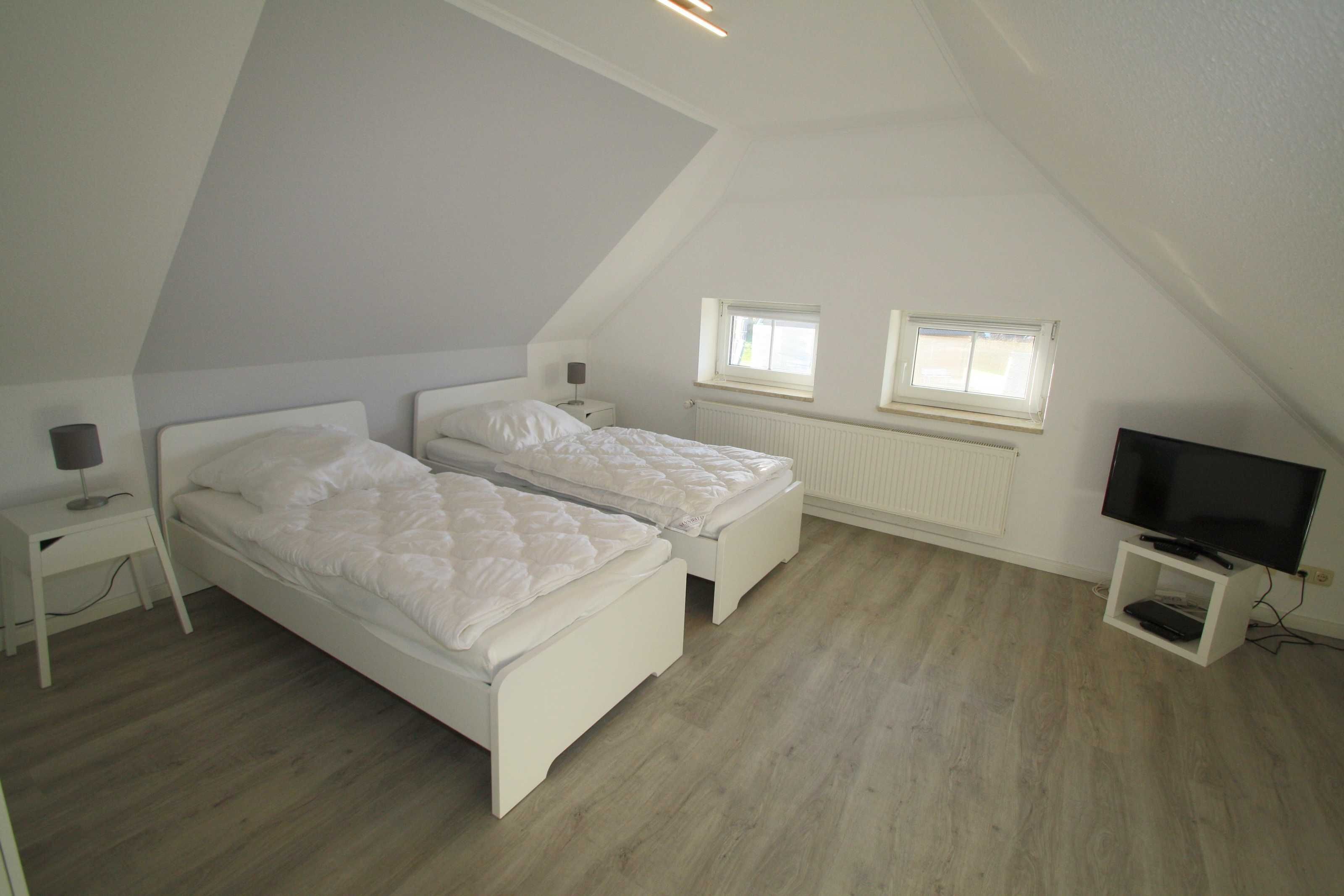 Een slaapkamer met twee bedden, een televisie en een raam.