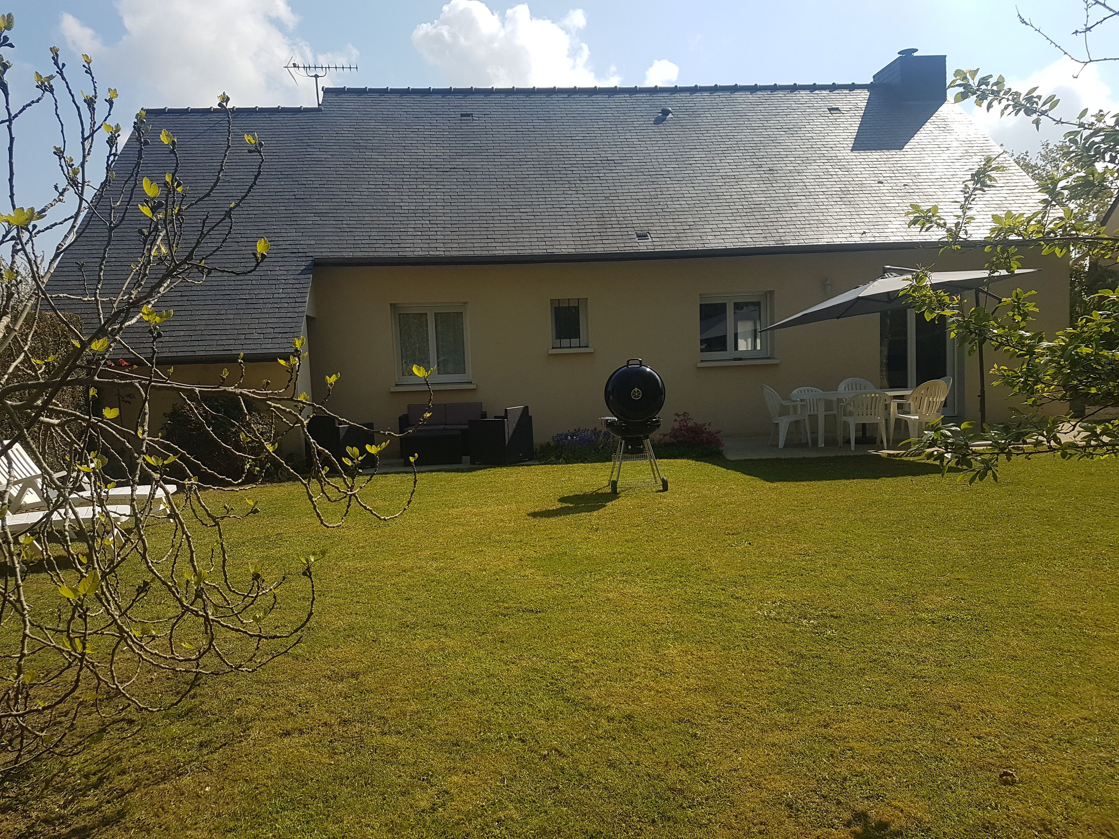 Ein Haus mit gepflegtem Rasen, Grill und Gartenmöbeln.