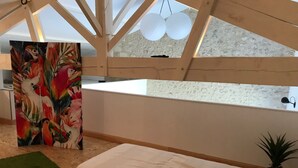 Ein Schlafzimmer mit einem großen Fenster, einem Papageienbild, einem grünen Teppich und einem Bett.