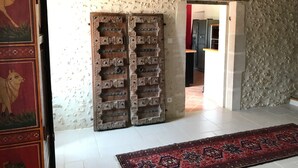 Ein rustikales Interieur mit einer Steinsäule, einer Holztür mit aufwendigen Schnitzereien und einem gemusterten Teppich auf dem Boden.