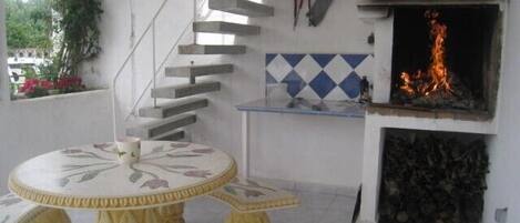 A dining area with a round table and matching stools, a fireplace, and a staircase.