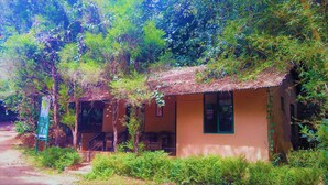 A rustic building with a thatched roof, surrounded by dense greenery. - Vythiri Greens Resort (Vythiri)