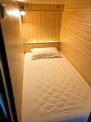 A small, single-bed room with wooden paneling and a bedside lamp. - Box Inn Jiufen - Hostel (New Taipei City)