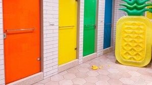 A row of brightly colored doors in a hallway with a pineapple-shaped object and rubber ducks on the floor. - Box Inn Jiufen - Hostel (New Taipei City)