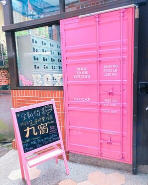 A pink storage box with weight capacity labels and a chalkboard sign with contact information. - Box Inn Jiufen - Hostel (New Taipei City)