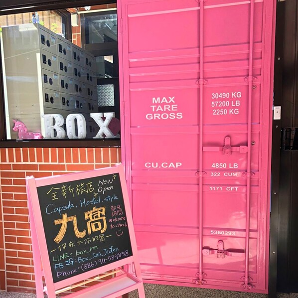 A pink container with weight limits and a chalkboard sign advertising a capsule hostel. - Box Inn Jiufen - Hostel (New Taipei City)