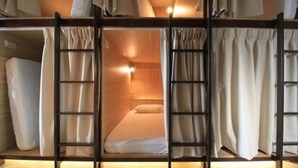 A bunk bed room with a ladder, curtains, and a bedside lamp. - Box Inn Jiufen - Hostel (New Taipei City)