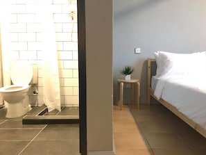 Ein Badezimmer mit Toilette, Dusche und einem kleinen Nachttisch mit einer Pflanze.