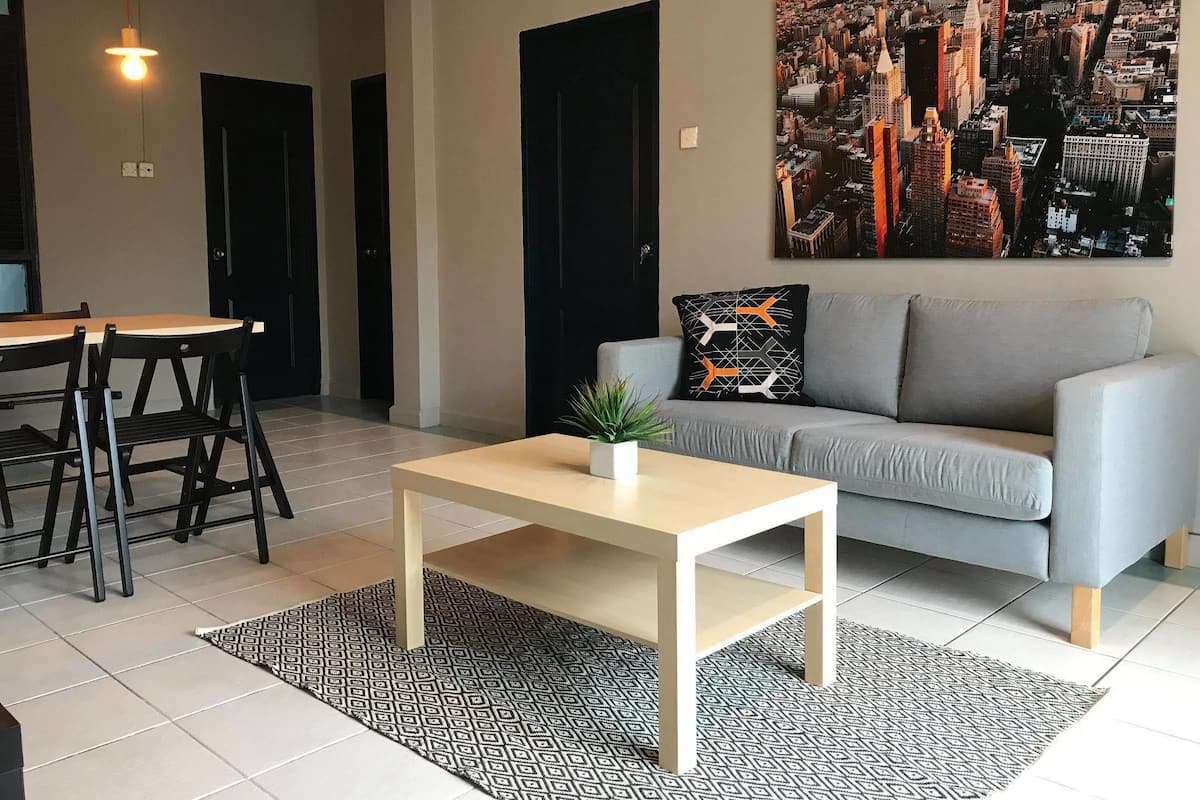 Una sala de estar moderna con un sofá gris, una mesa de centro y un cuadro de un paisaje urbano en la pared.