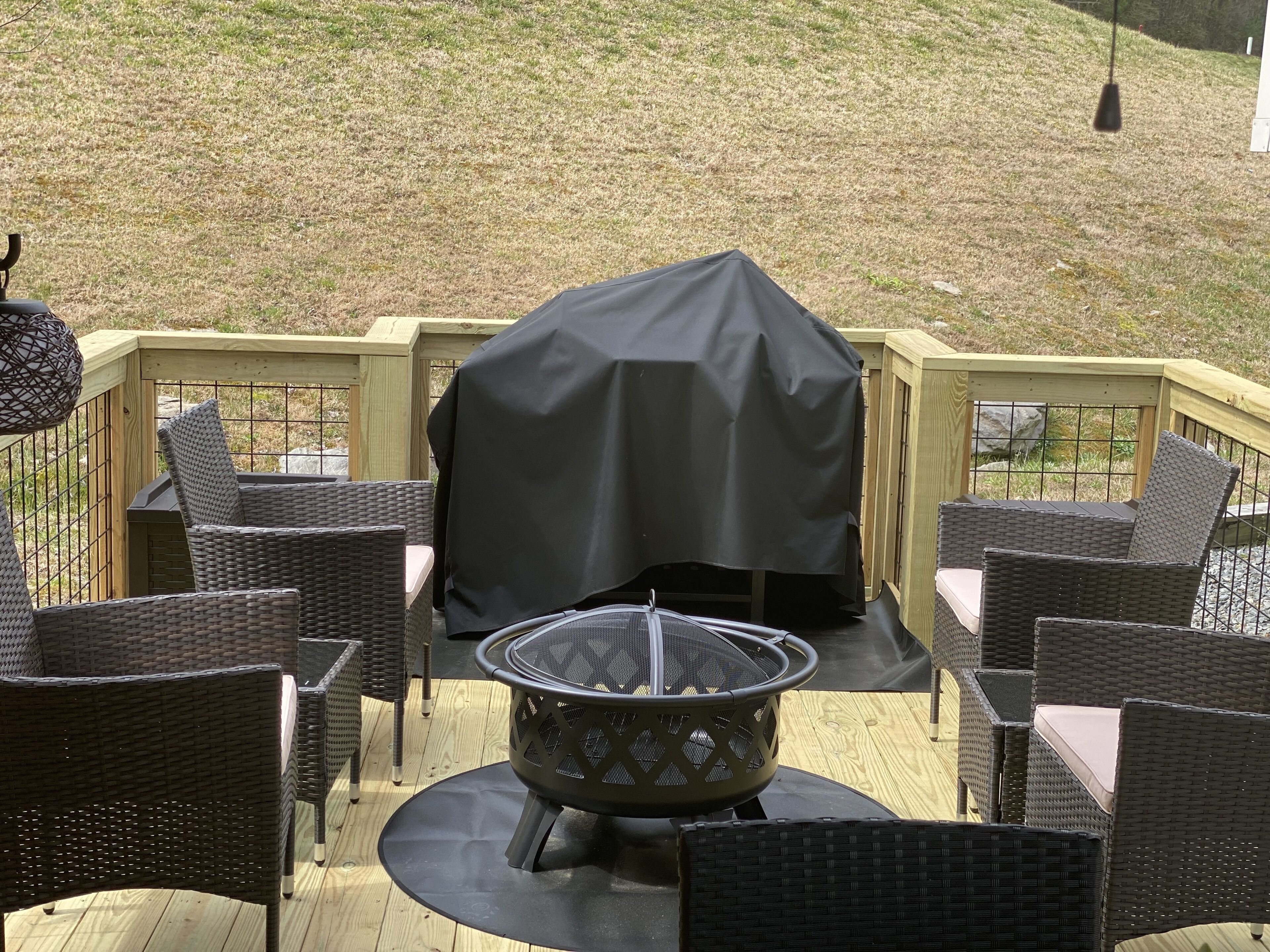 A deck with wicker furniture and a covered grill.