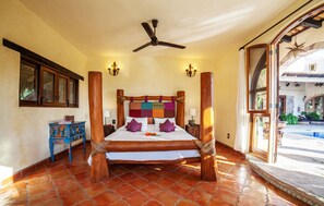 A spacious bedroom with a large bed, wooden headboard, and a ceiling fan.