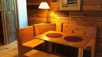 Une table à manger en bois, avec des bancs, une lampe et un tableau encadré accroché au mur.