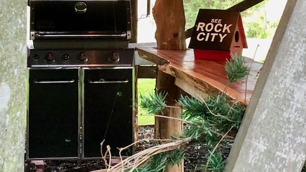 Una zona de cocina al aire libre con una parrilla, horno y lámparas colgantes.