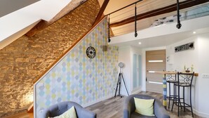 Een modern interieur met een stenen muur, een muur met een geometrisch patroon, en een eetgedeelte met barstoelen.