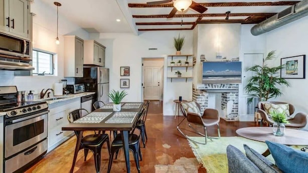 Una cocina moderna con comedor, una sala de estar con sofá y sillones, y vistas al horizonte de la ciudad.