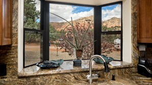 A kitchen with a granite countertop, a sink, and a window with a view of a desert landscape. - Pet Friendly
Hike, Bike, Enjoy! (Sedona)