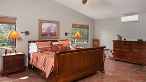 A bedroom with a wooden bed, two bedside lamps, a dresser, and a painting on the wall. - Pet Friendly
Hike, Bike, Enjoy! (Sedona)