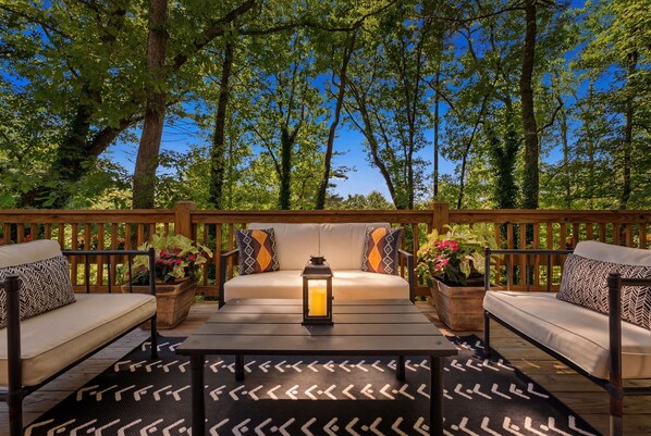Eine Terrasse mit einer Couch, zwei Beistelltischen, einer Laterne und Topfpflanzen.