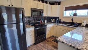 A kitchen with a refrigerator, stove, microwave, and oven.
