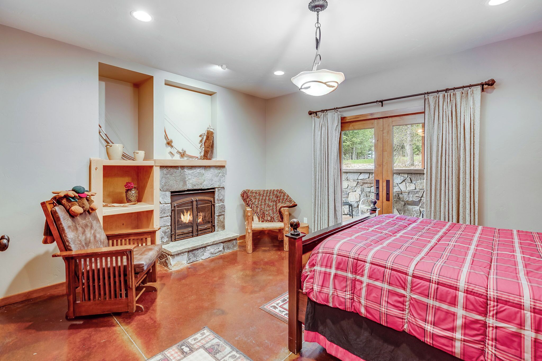 Une chambre à coucher avec un lit, une cheminée, une fenêtre avec des rideaux et une chaise en bois.
