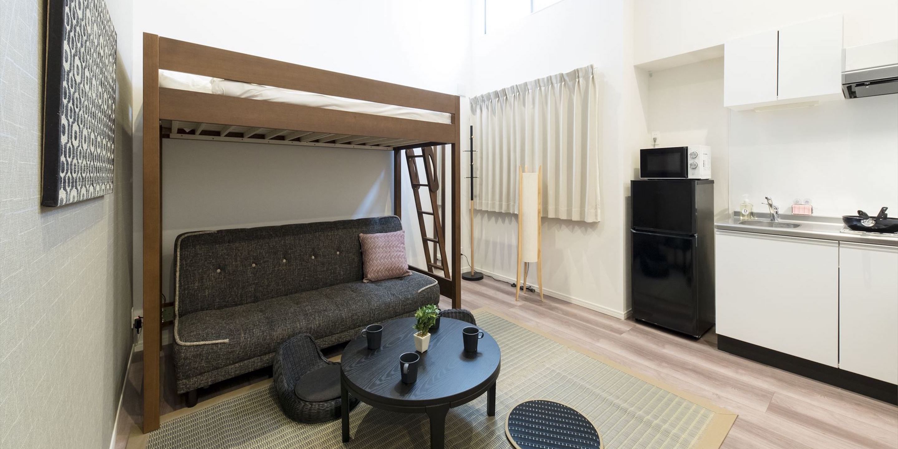 Un espacio habitable compacto con sofá, una mesita, televisor y kitchenette.