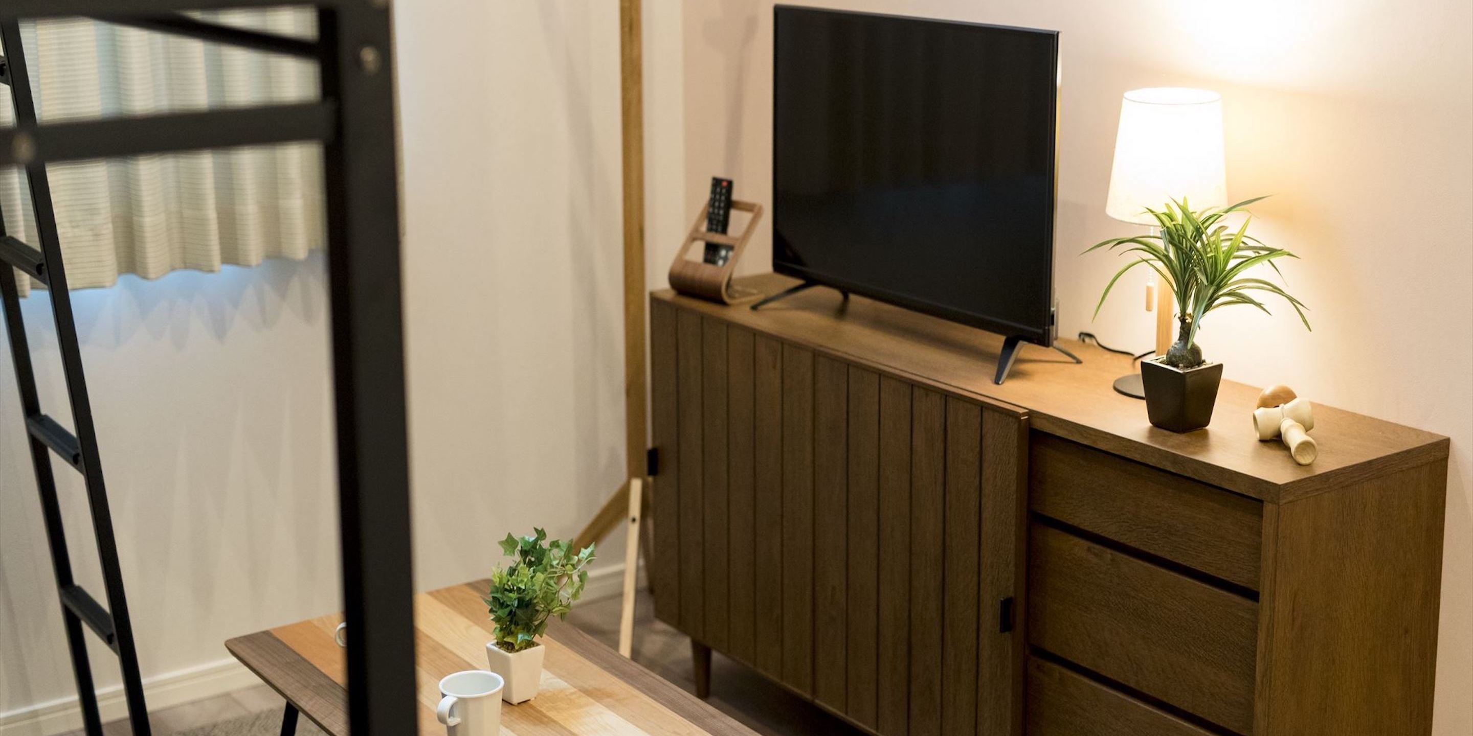 Ein TV-Schrank aus Holz mit Fernseher, einer Lampe und einem Blumentopf.