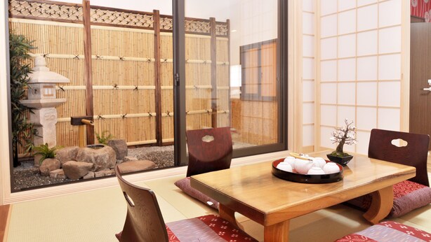 A traditional Japanese room with tatami flooring, a low table with a tea set, and a view of a bamboo fence and garden outside. - Shirakabanoyado-fuka (Osaka)