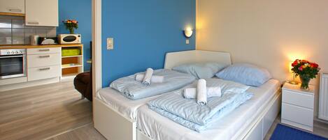 A bedroom with a bed, bedside table, and a small kitchen area with a microwave and toaster.