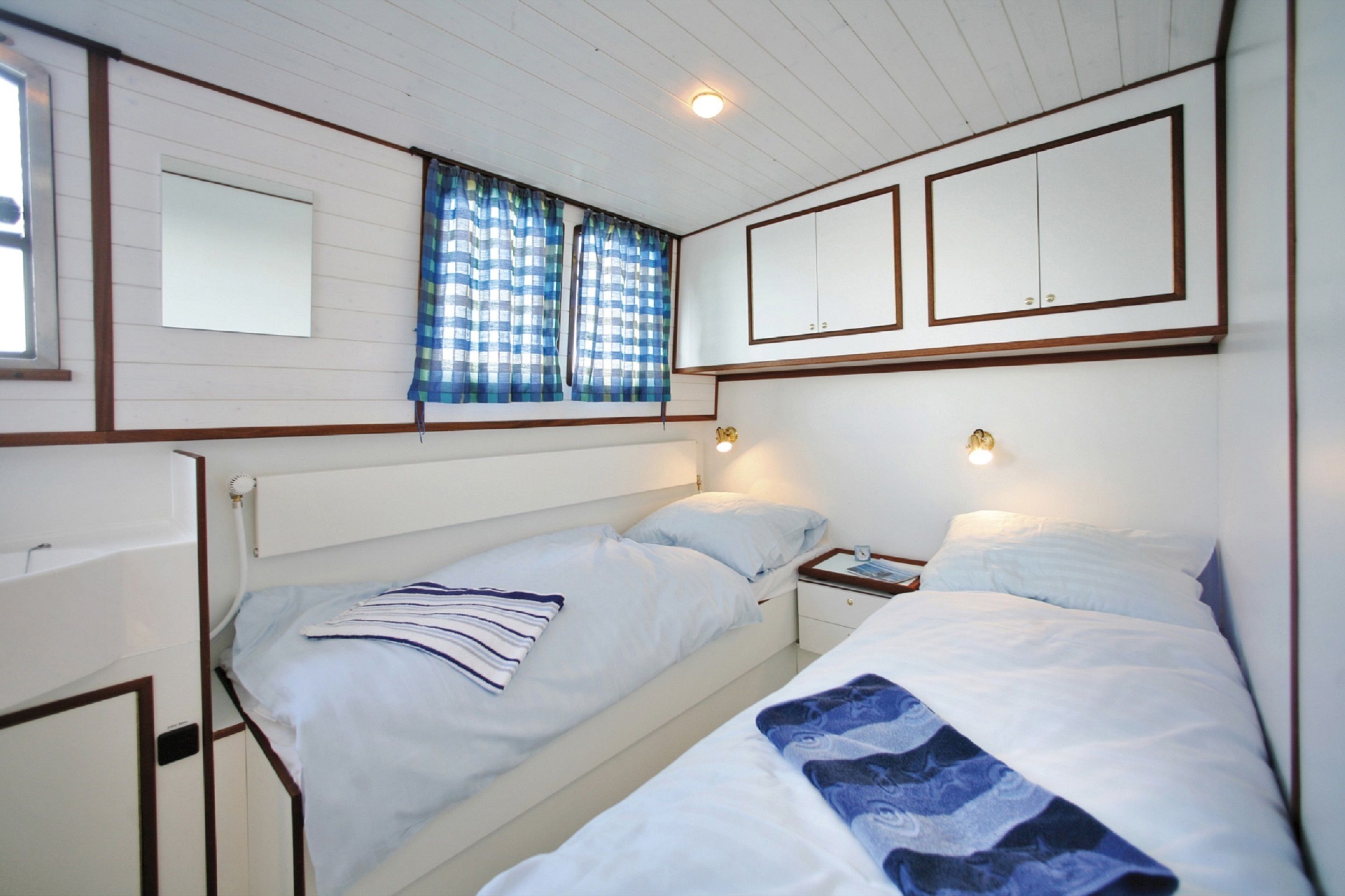 Una habitación con dos camas individuales, una ventana con cortinas, un espejo y un armario.