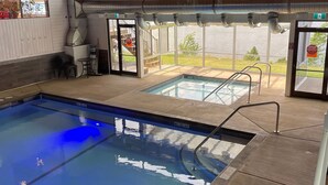 An indoor swimming pool with clear water, a diving board, and a view of a lake through large windows. - Private beach and lake access at Windermere Lake. NEW POOL AND HOT TUB NOW OPEN! (Windermere)