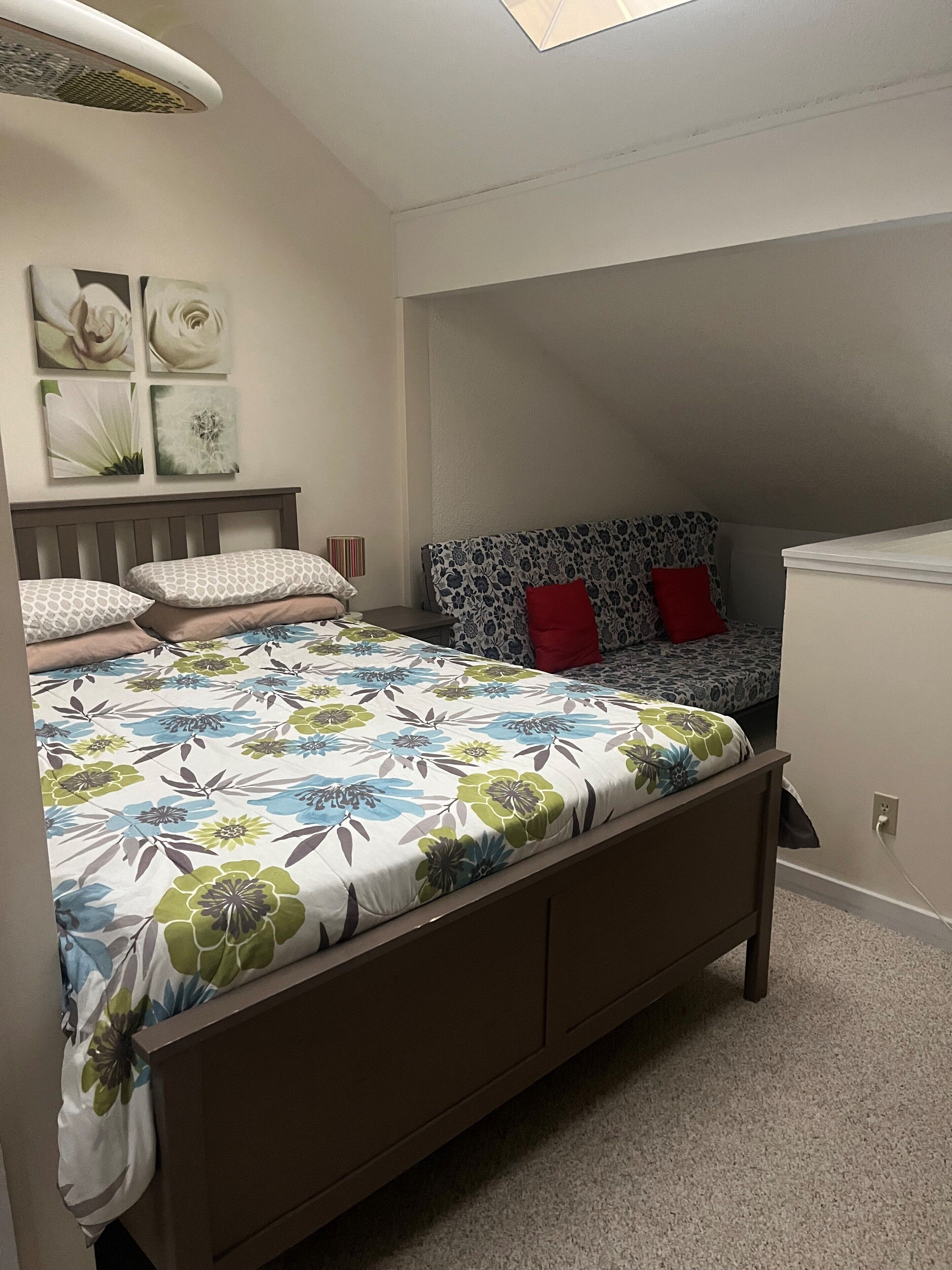 A bedroom with a bed, a nightstand, a lamp, and a wall with artwork.