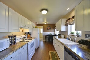 A kitchen with white cabinets, a stove, and a sink.