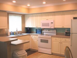 A kitchen with white cabinets, a microwave, stove, and a toaster.