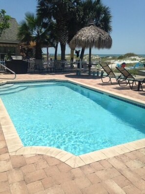 Una piscina rectangular con agua azul cristalina, rodeada por una solana con mosaicos y sillas de descanso.