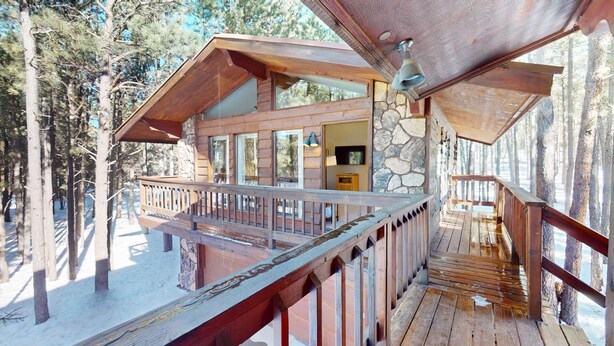 A cabin with a wooden deck, stone walls, and large windows.