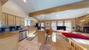 A spacious kitchen with wooden cabinets, a central island, and a dining area with a red couch.