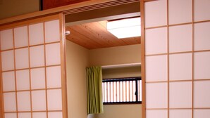 A room with two beds, a sliding shoji screen, a green curtain, and a window with blinds. - Shirakabanoyado-keigetsu (Osaka)